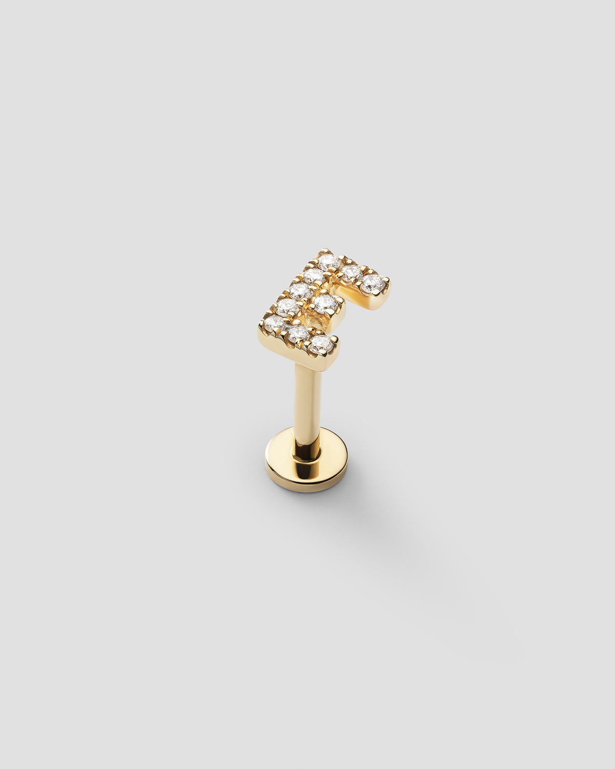 Letter labret in 14k yellow gold, detail view.