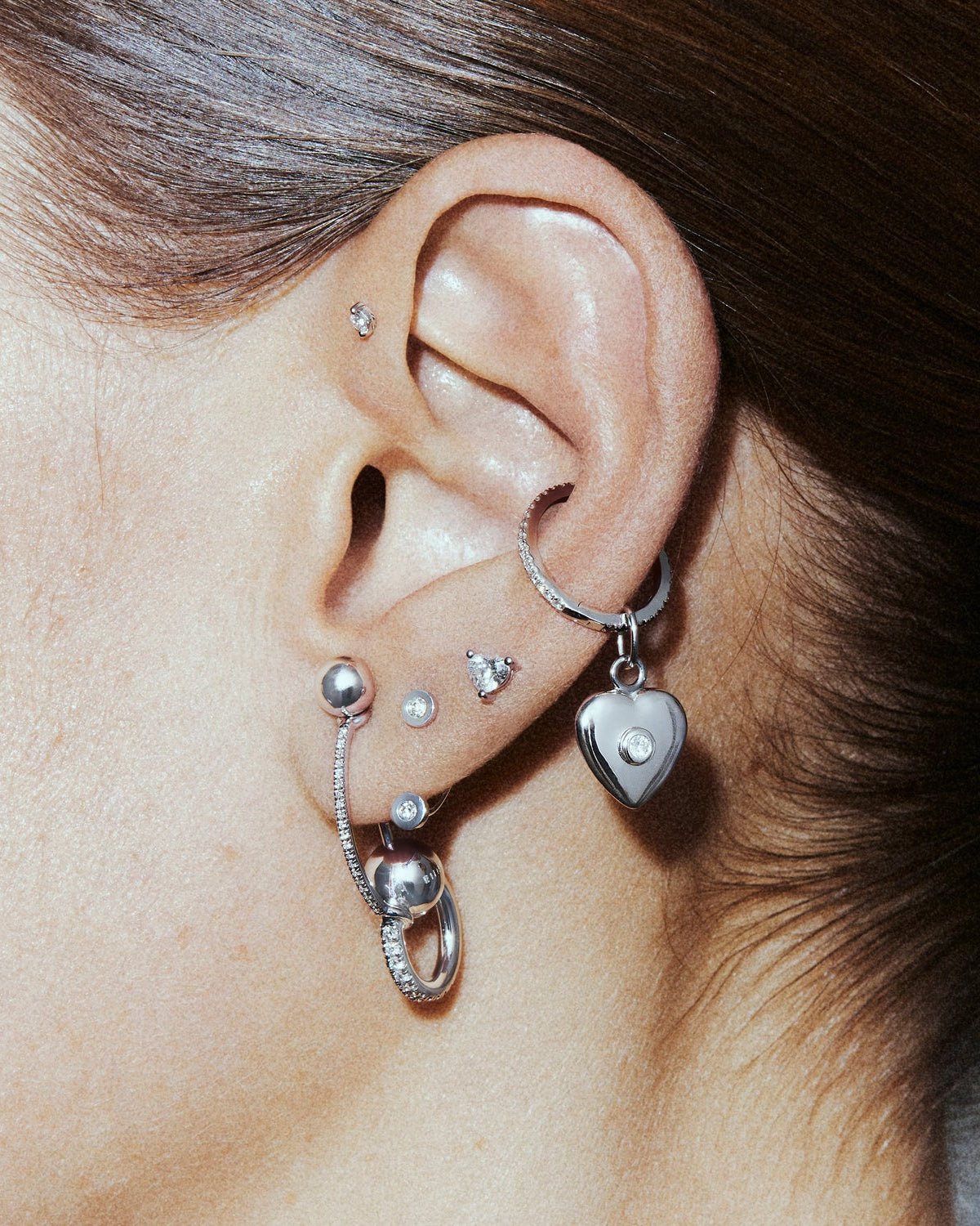 A styled ear from the Punk set, with a heart labret, an arch, a hoop and the Castor and Ivory pieces.