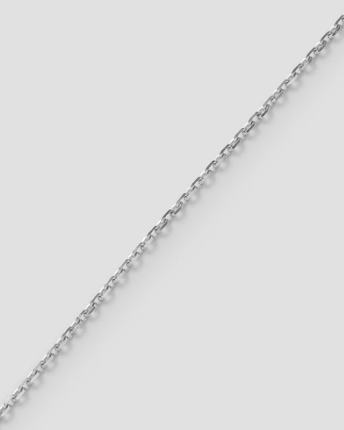 Diamond cut mirror chain, 1.0 mm, in 18k recycled white gold, laid diagonally on a pale ground.