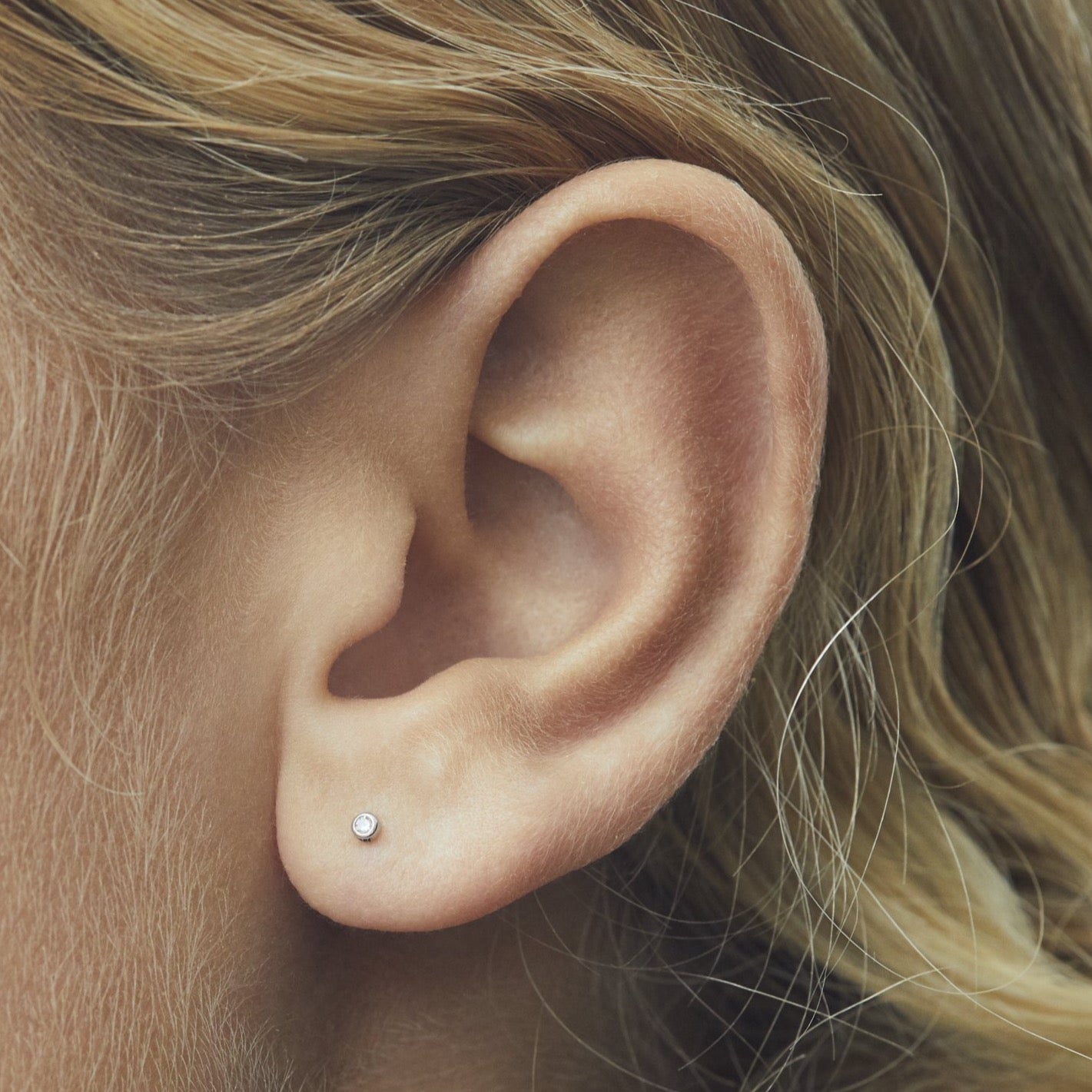 single stone labret with white diamond set in white gold on ear