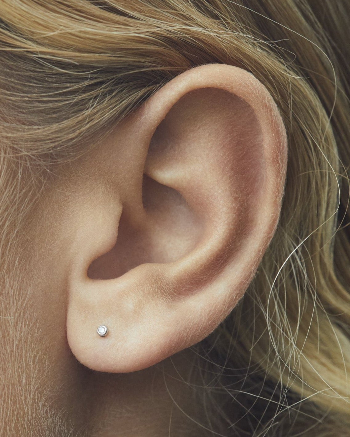 single stone labret with white diamond set in white gold on ear