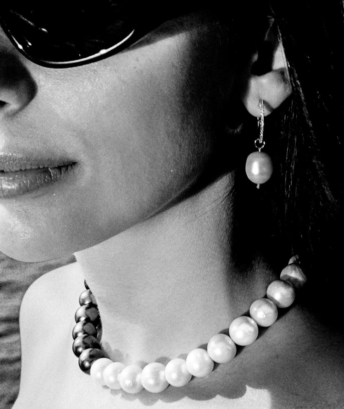 Era pearl necklace and a pearl drop earring, worn, in black and white.