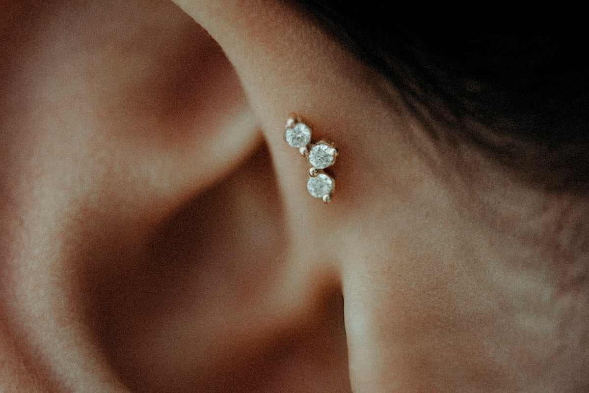Close-up of an ear with three round diamond labrets set in a line along the lobe.