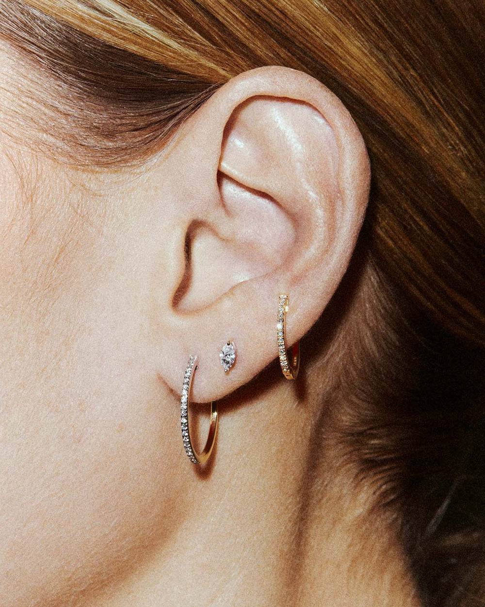 An ear styled with a marquise-cut diamond labret in the high lobe and a slim diamond hoop below.
